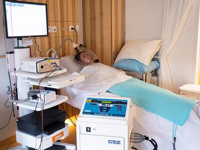 Marion Laseere in een ziekehuisbed aangesloten op diverse meetapparatuur